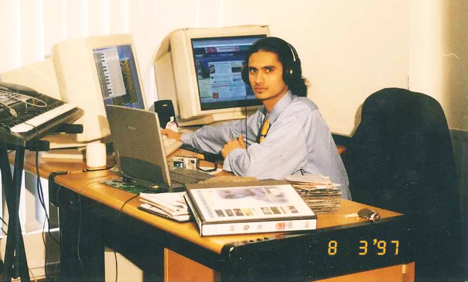 Naushad at his desk in March 1997 — two beige CRT monitors, one showing a web page, an early laptop, a MIDI keyboard, and a camera date stamp reading 8 3'97.
